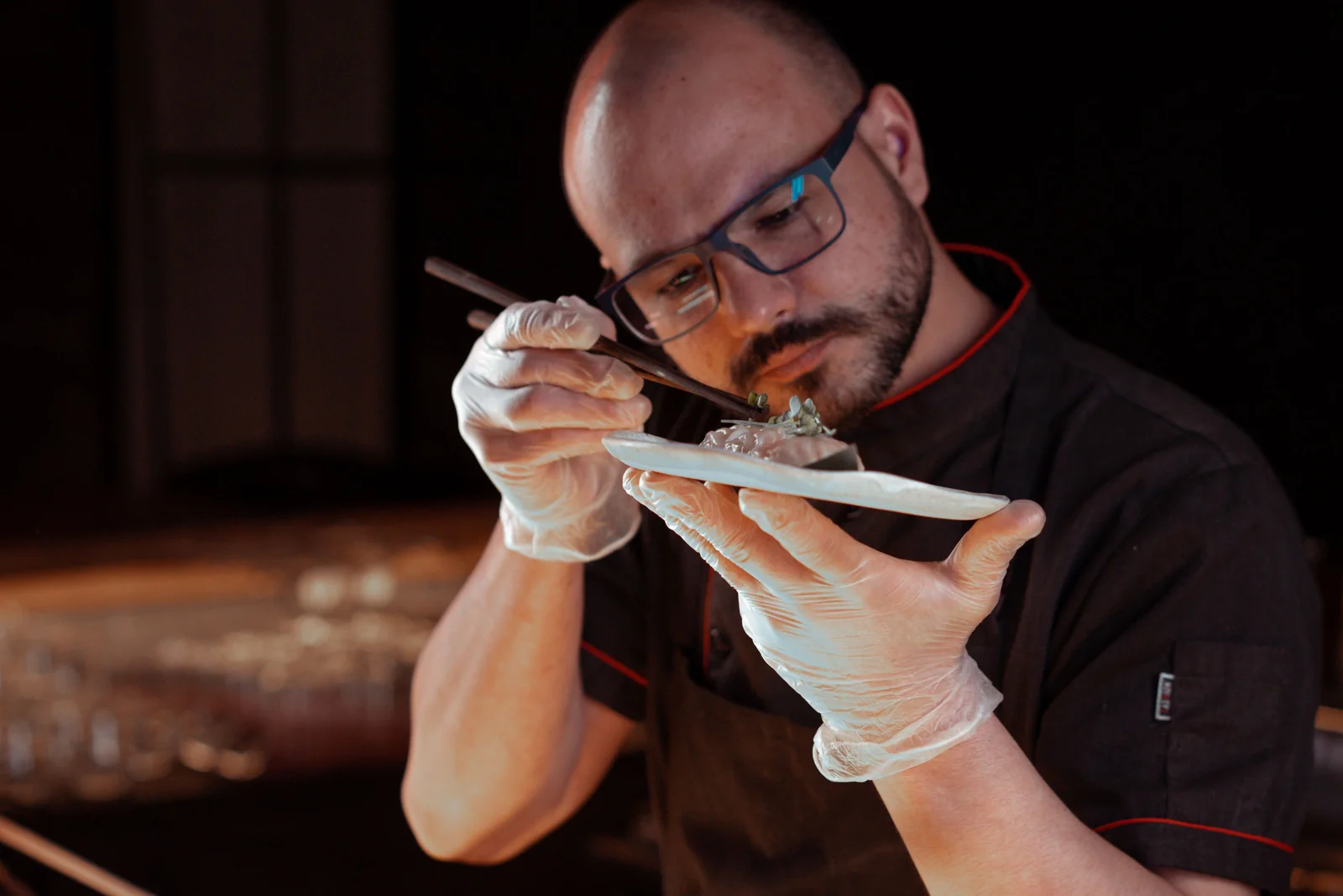 Chef afinando con pinzas la presentación de un plato.